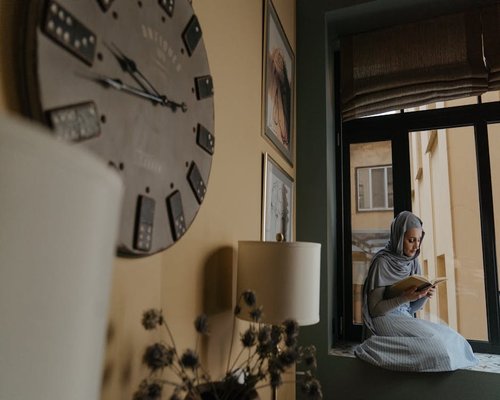 Middle aged person reading a book comfortably by the window